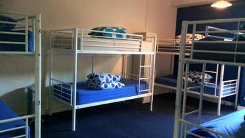 Un dormitorio con literas, alfombra azul y ventilador de techo.