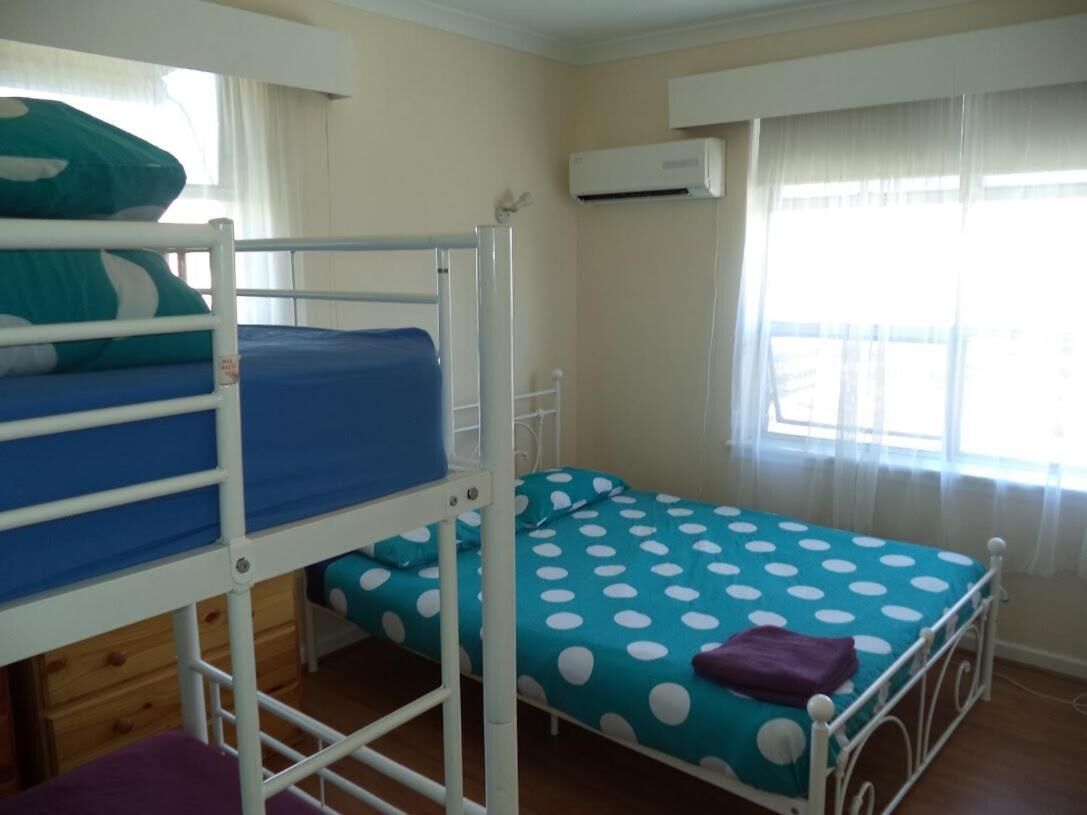 A room with bunk beds, a window with curtains, and an air conditioning unit.