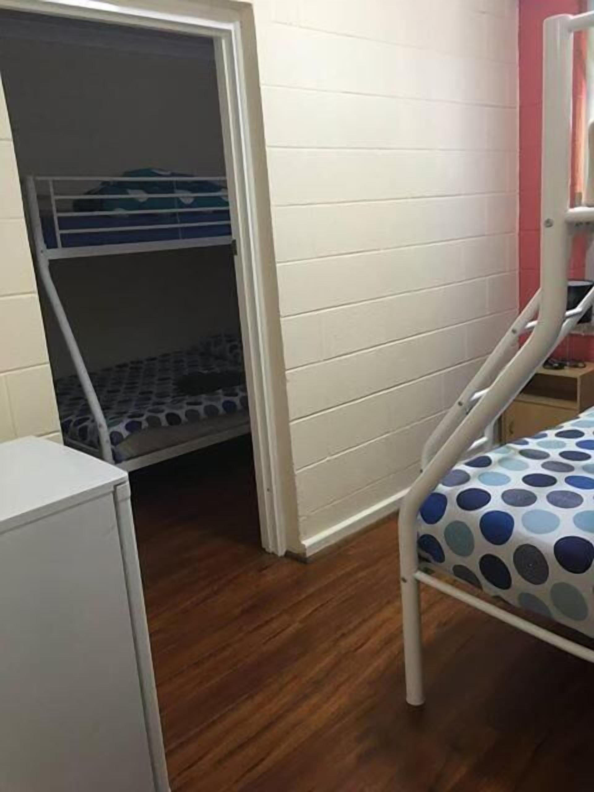 A bunk bed with a polka dot mattress, a white wardrobe, and a small table.