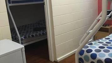 A bunk bed with a polka dot mattress, a white wardrobe, and a small table.