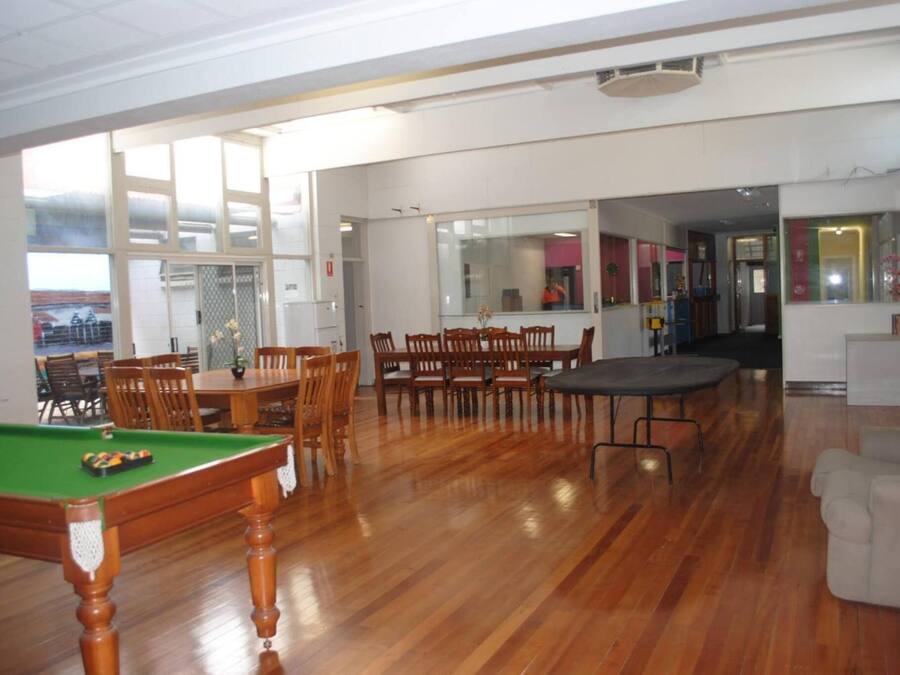 A spacious room with a pool table, multiple wooden chairs, and a dining table.