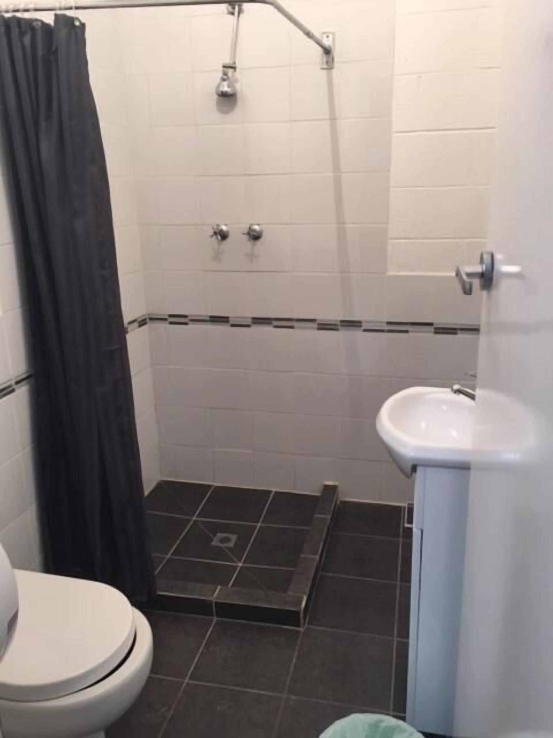 A small bathroom with a toilet, a sink, and a shower.