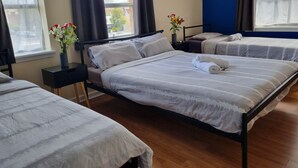 Habitación de hotel con dos camas, una ventana, una mesita de noche y un florero con flores.