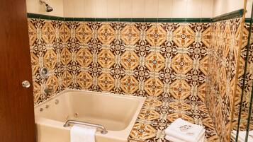 Une salle de bain avec une baignoire, une douche et des carreaux décorés.