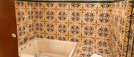 A bathroom with a bathtub, a shower, and patterned tiles.