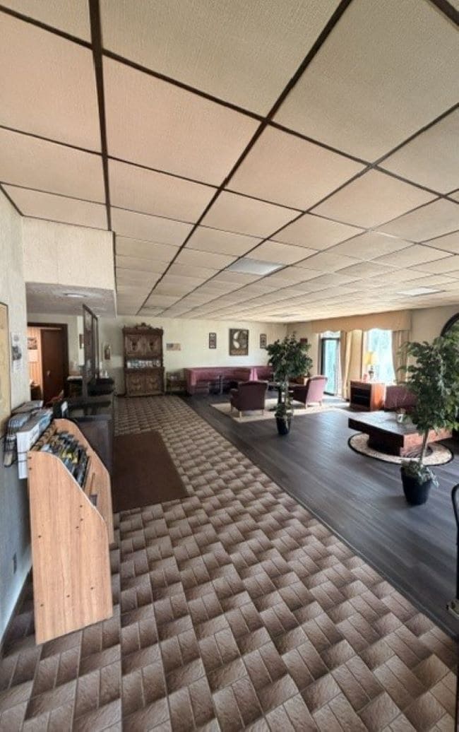 A spacious lobby with a checkered floor, a reception desk, seating areas, and potted plants.