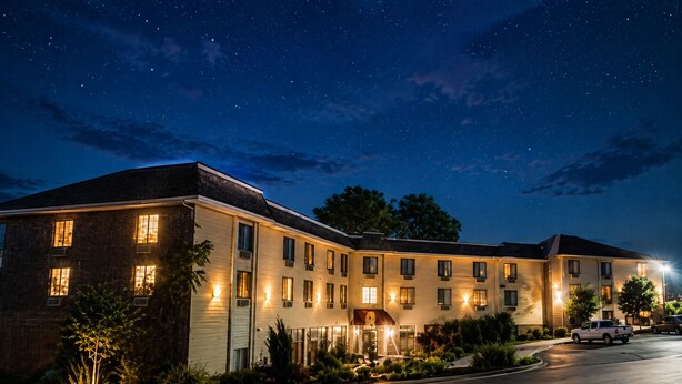 Um hotel com vários andares, fachada de tijolos, várias janelas e uma entrada bem iluminada.