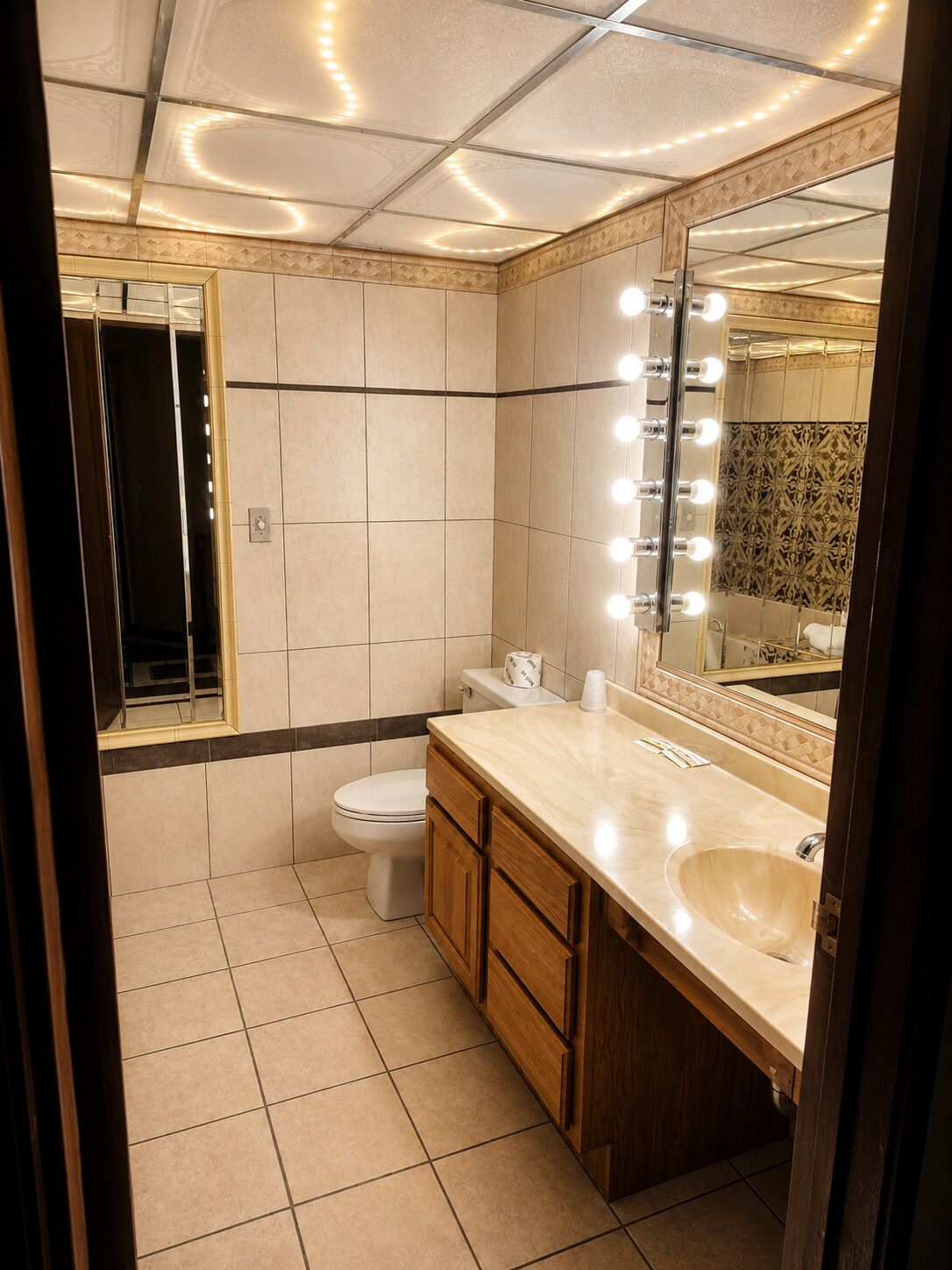 A bathroom with a vanity, mirror, and lights.