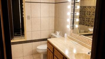A bathroom with a vanity, mirror, and lights.