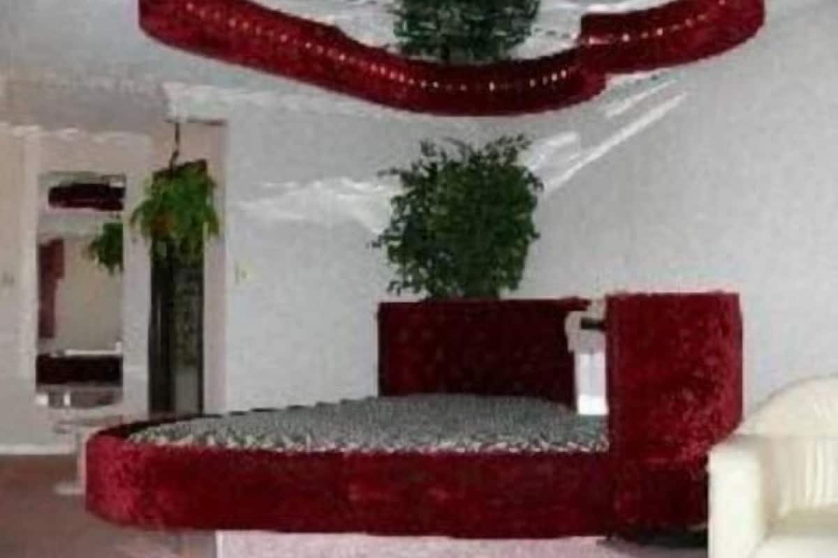 A room with a red sofa, a small table, and a potted plant.