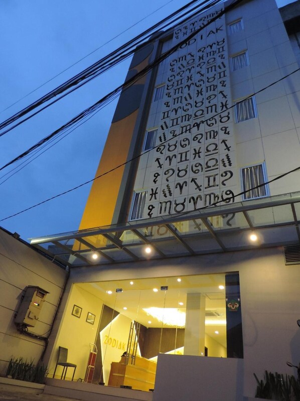 Un bâtiment doté d’une grande enseigne affichant divers symboles et du texte, d’une entrée en verre et d’un espace d’accueil sur lequel on peut lire l’inscription « ZODIAK ».