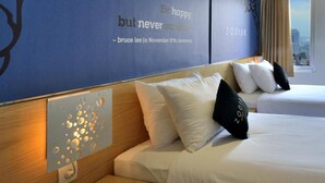 A hotel room with two beds, a decorative blue wall with a quote, and a city view. - Zodiak Kebonjati by KAGUM Hotels (Bandung)