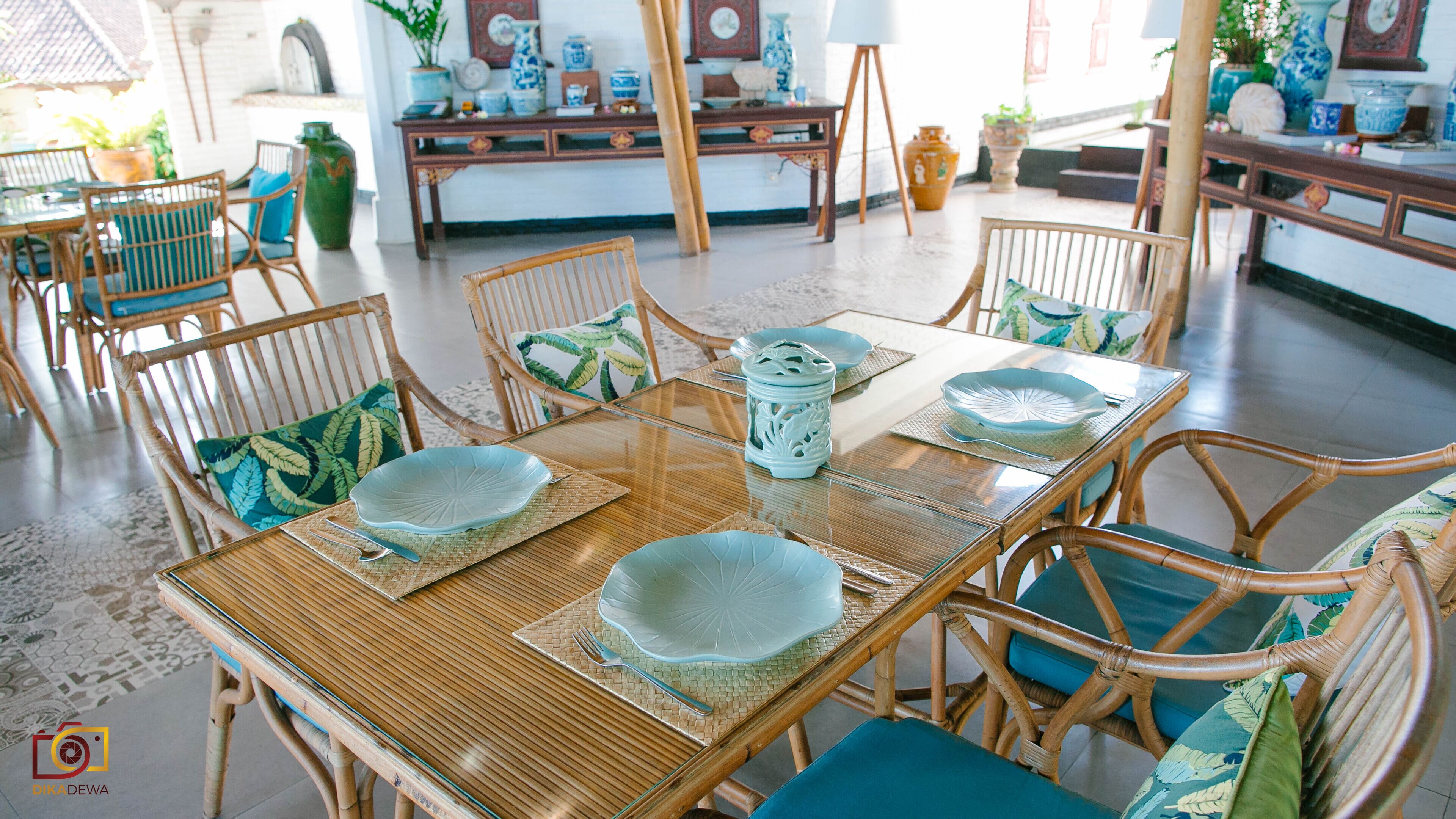 A dining area with a wooden table, wicker chairs, and blue cushions.