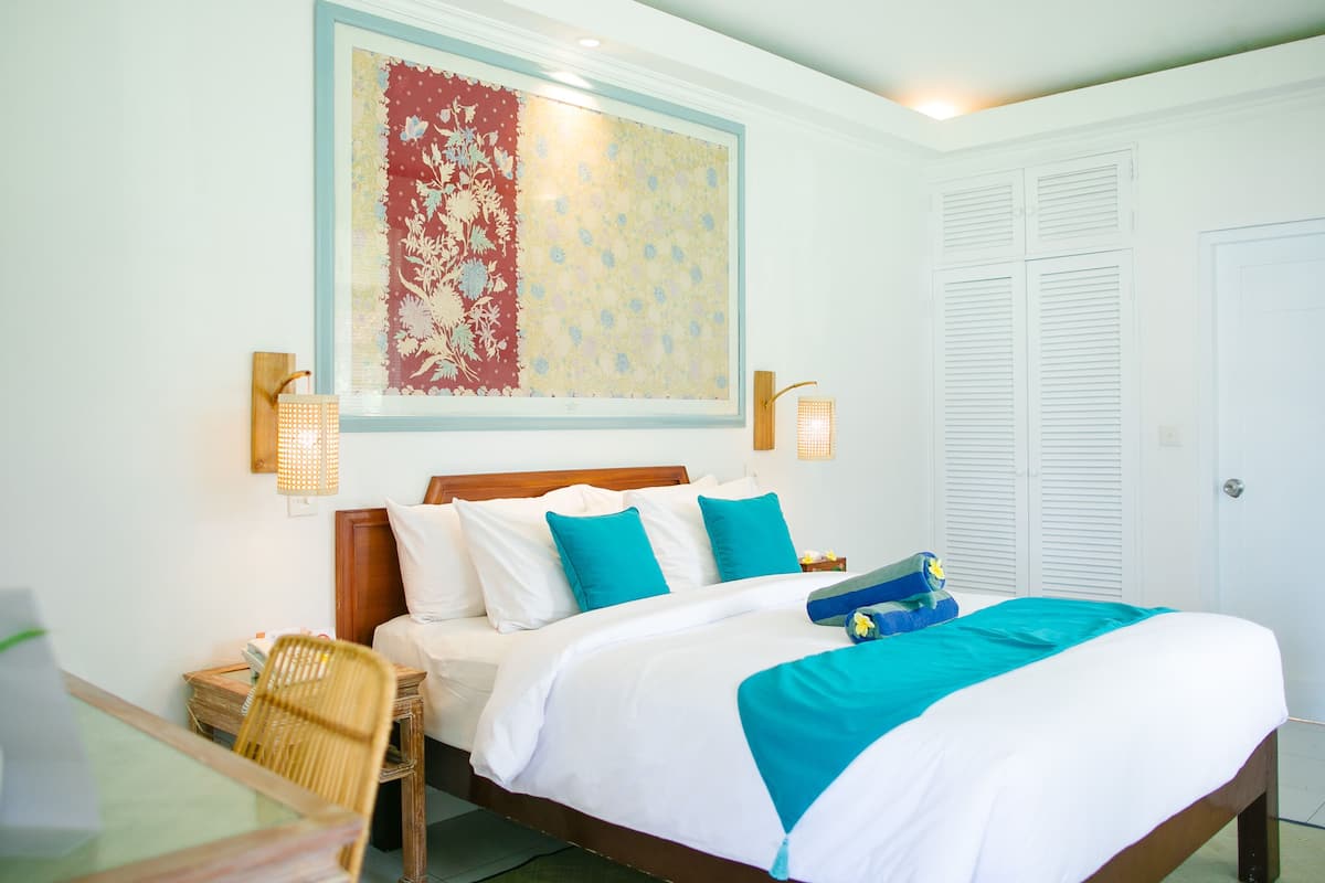 A neatly arranged bedroom with a bed, bedside tables, a chair, and a wall-mounted lamp.
