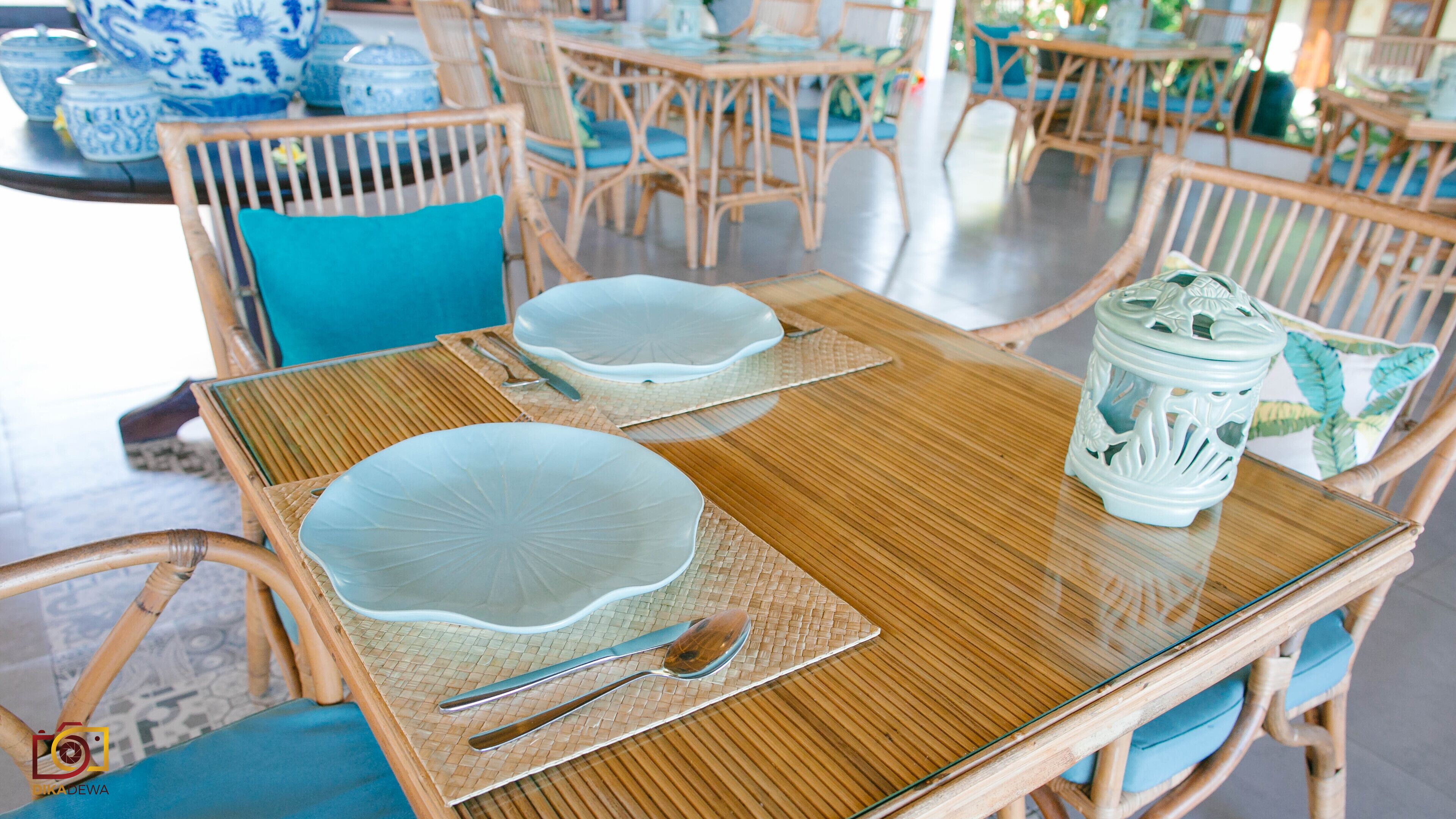 A dining table with two white plates, a spoon, and a decorative ceramic piece.