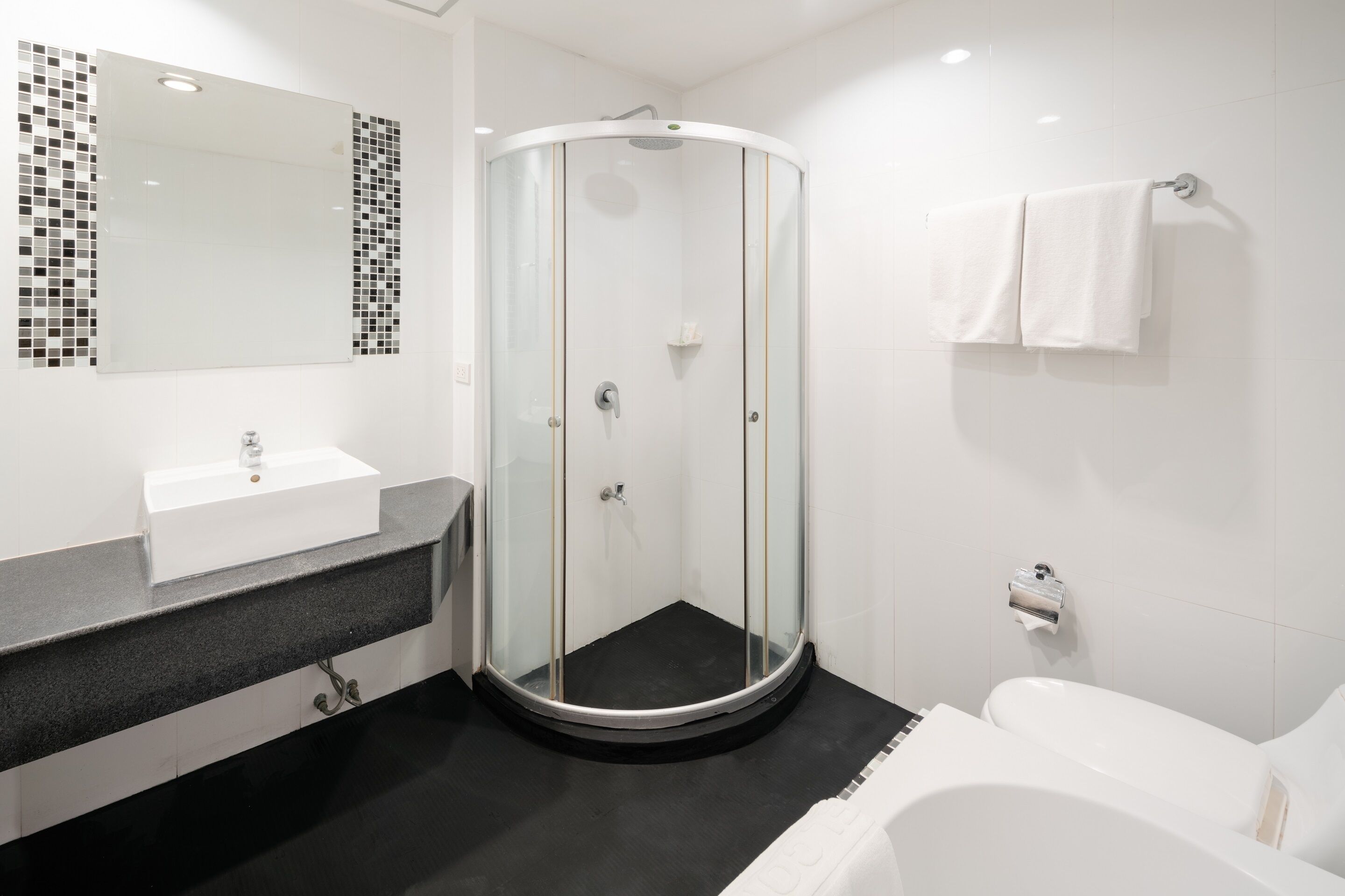 Un baño moderno con ducha envuelta en vidrio, un lavabo blanco y una bañera.