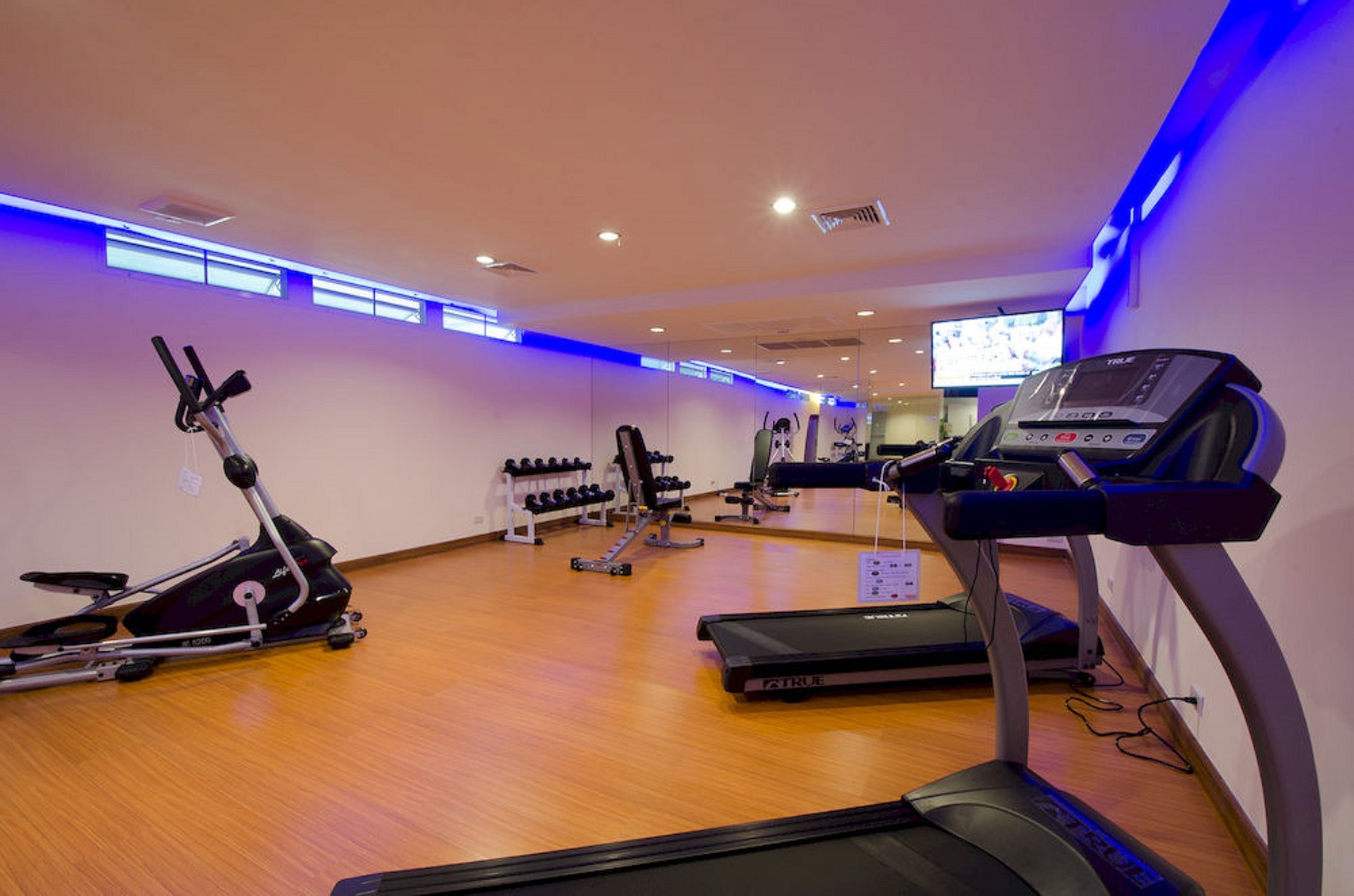 Un gimnàs amb cintes de córrer, el·líptiques i bancs de musculació.