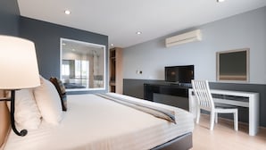 A modern bedroom with a bed, bedside table, lamp, TV, and a desk with a chair. - iCheck Inn Residences Sathorn (Bangkok)