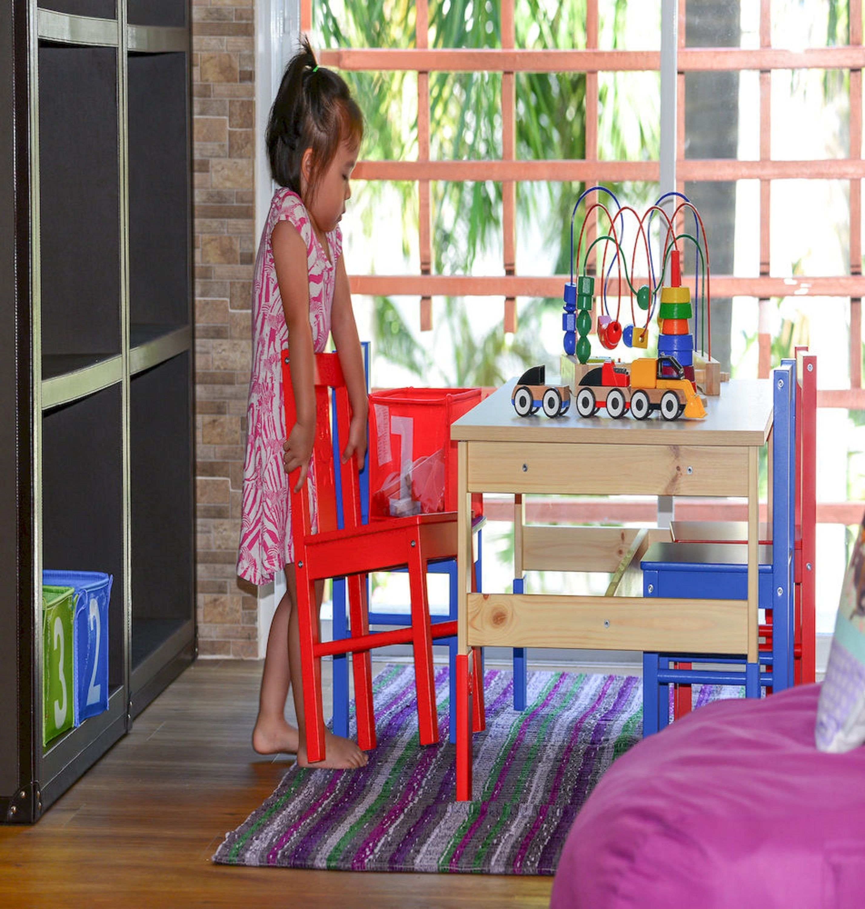 A child playing with toys near a window with a view of greenery.