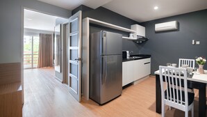 A modern kitchen with a stainless steel refrigerator, white cabinets, and a dining area with a white table and chairs. - iCheck Inn Residences Sathorn (Bangkok)