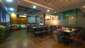 Un restaurant spacieux avec de hauts plafonds, de grandes fenêtres et différents types de mobilier, notamment des tables et des chaises.