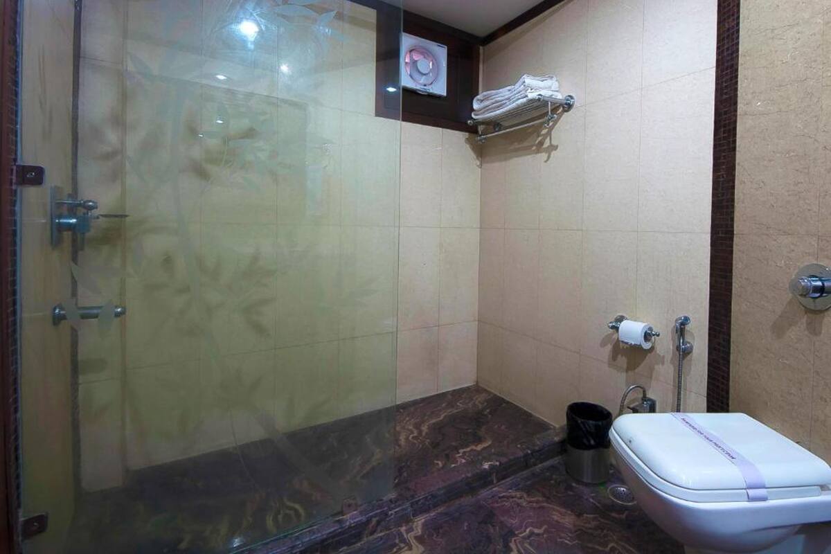 Un baño con cabina de ducha de vidrio, inodoro y perchero para toallas.