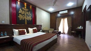 Une chambre d’hôtel avec un grand lit, un bureau, une chaise et une armoire.