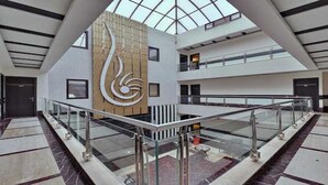 A spacious atrium with a high ceiling, a central wooden sculpture, and a glass railing. - Hotel Blue Pearl (New Delhi)