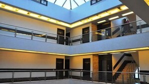 A multi-level interior with glass railings and a central staircase. - Hotel Blue Pearl (New Delhi)
