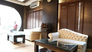 A living room with a glass coffee table, a white sofa, and a beige armchair. - Hotel Blue Pearl (New Delhi)