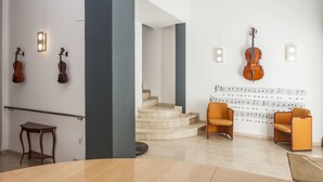 Un intérieur moderne avec un escalier, deux pupitres pour violons et un mur orné de partitions.