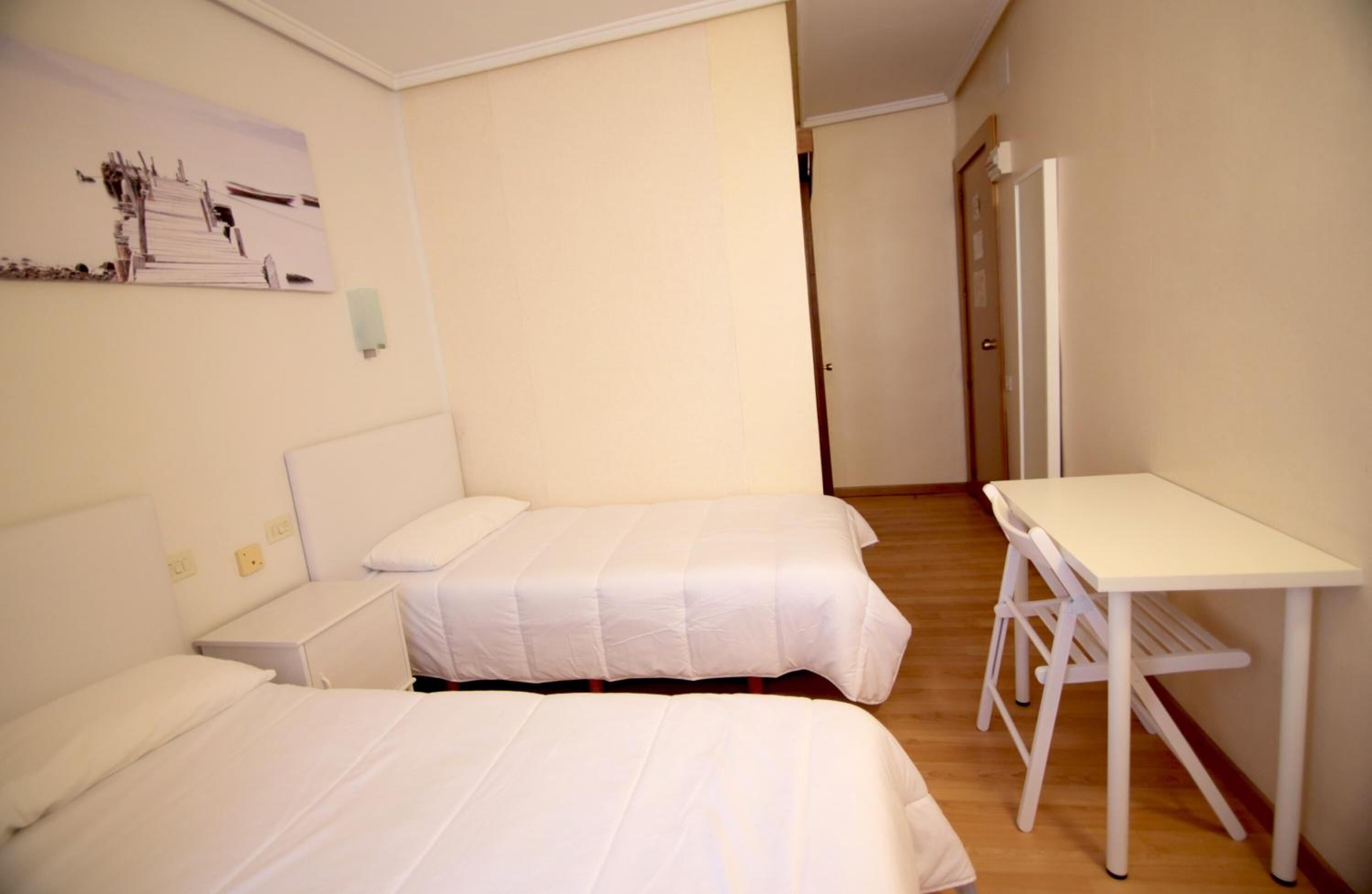 A room with two beds, a desk, and a door.