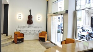 Une pièce où l’on trouve un violon, un piano et une chaise, avec des partitions accrochées au mur.
