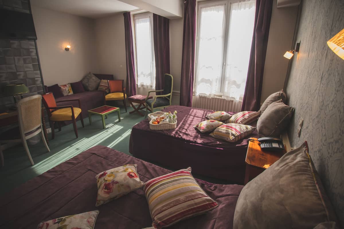 A cozy room with a bed, a sofa, a chair, and a small table.