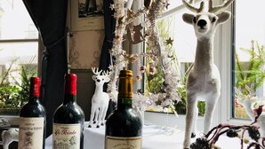 Una mesa con tres botellas de vino y una figurita de ciervo.