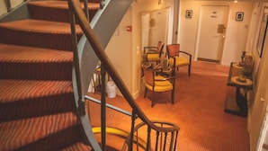Una escalera de caracol con barandilla metálica que conduce a una zona de descanso con una mesa y sillas.
