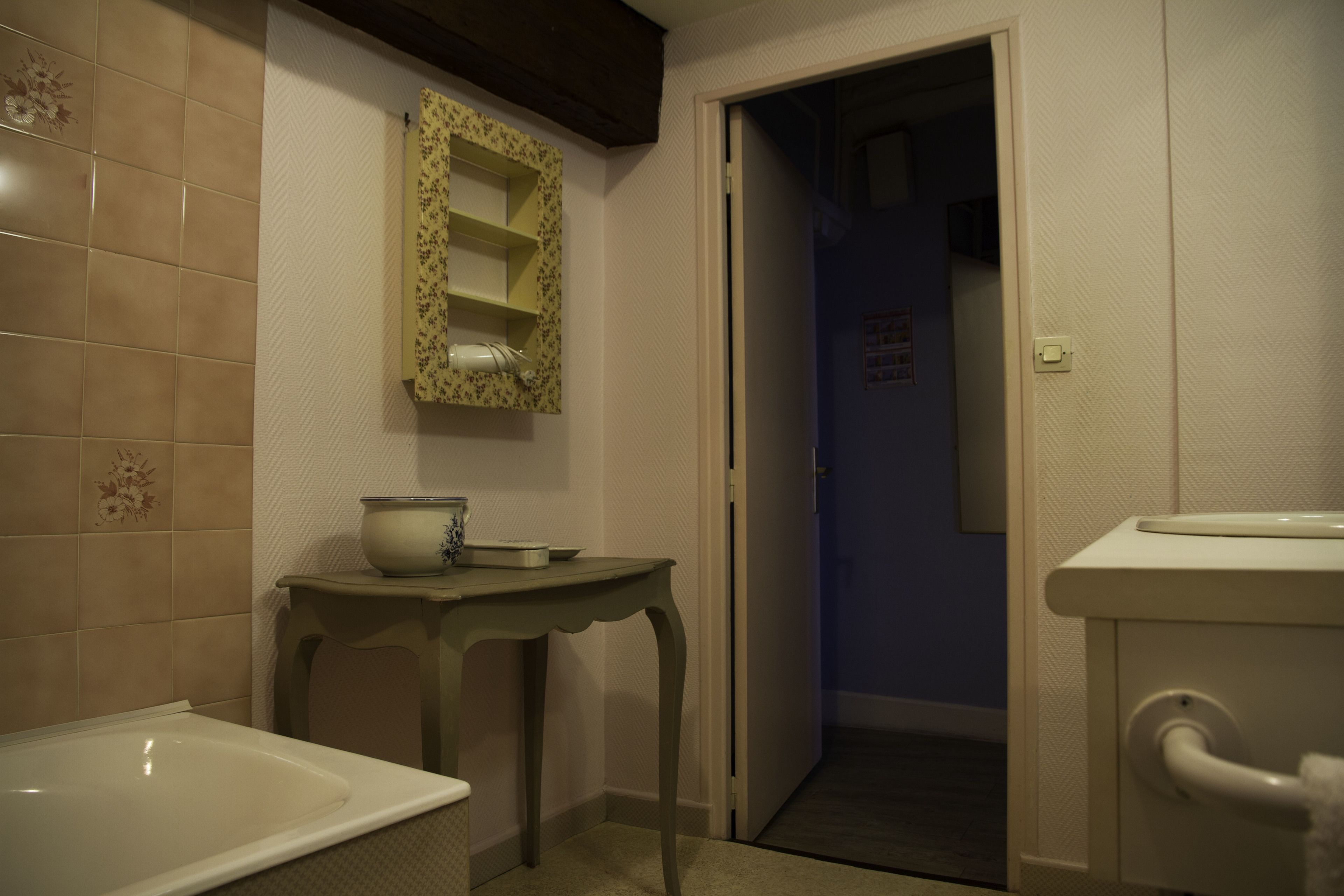 A bathroom with a bathtub, a sink, and a toilet. There is a mirror with a floral frame above the sink.