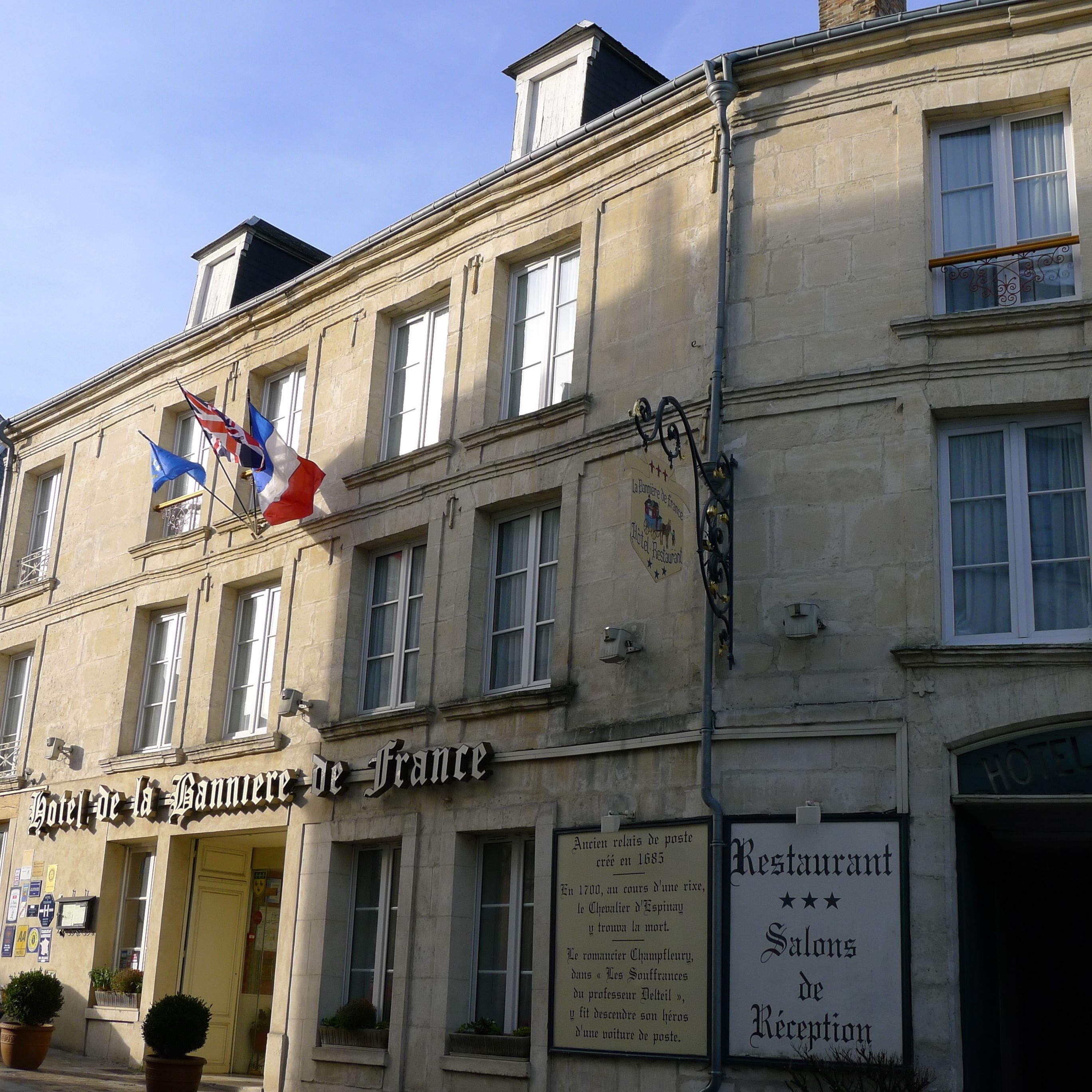 A historic building with a sign reading "Hotel de la Bannière de France" and a plaque detailing its history.
