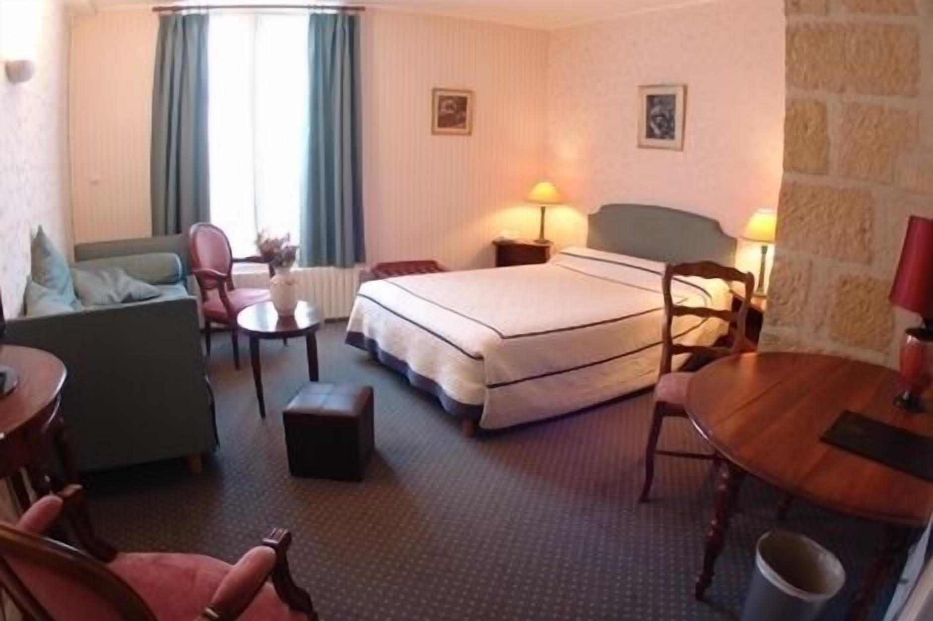 Een hotelkamer met een bed, een bureau, een stoel, een bank en twee lampen.