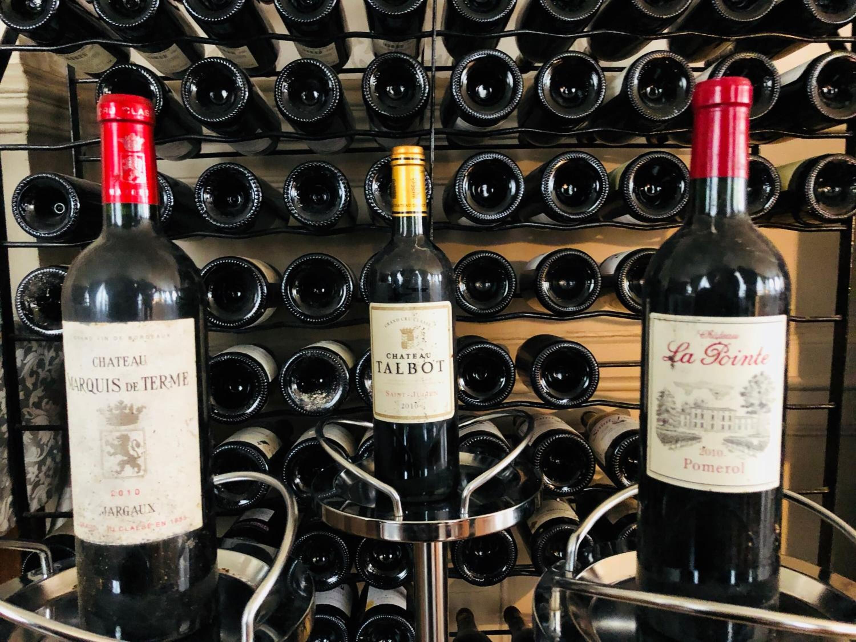 A wine rack with bottles of Chateau Marquis de Terme, Chateau Talbot, and La Fonte.