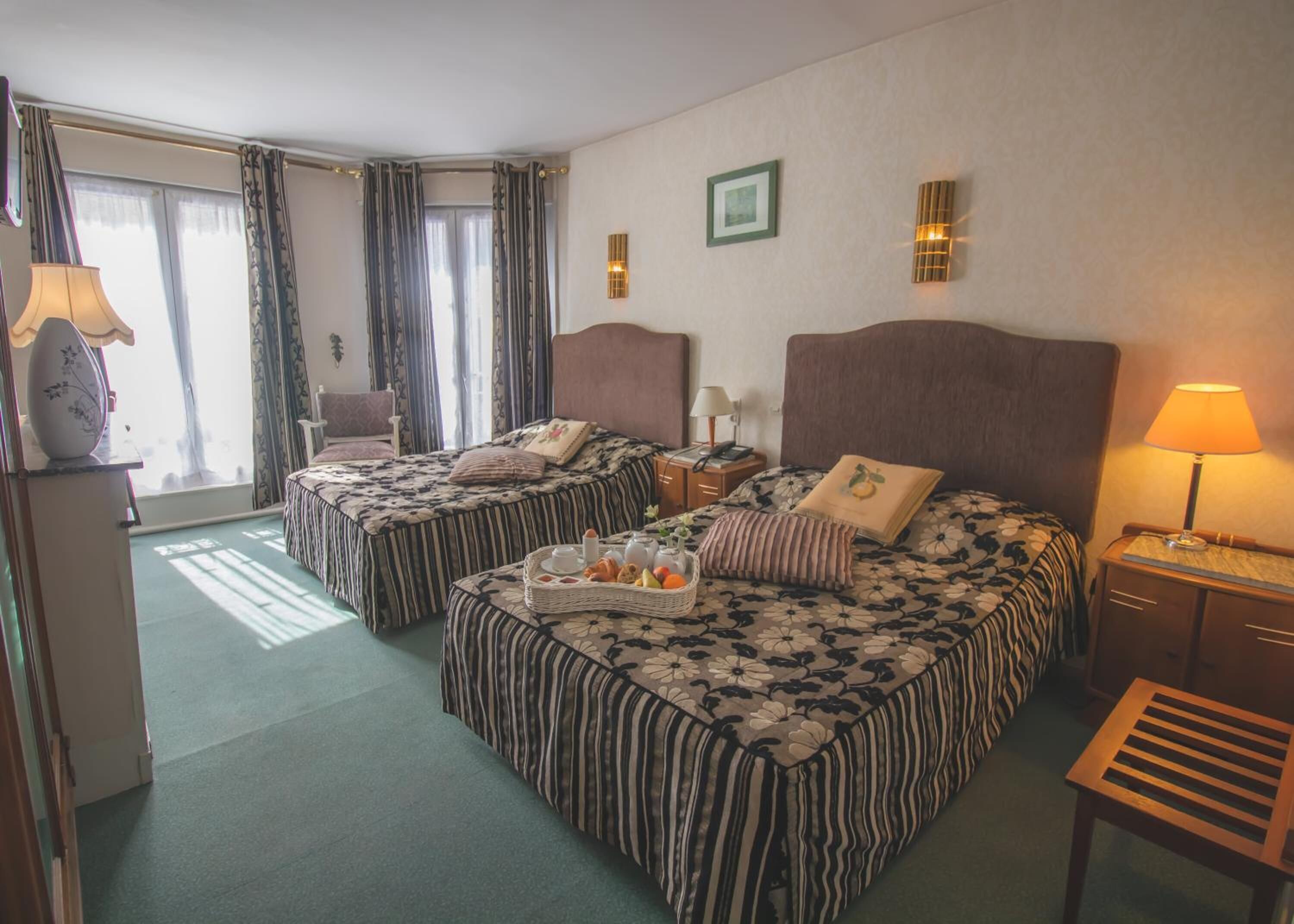 Ein Hotelzimmer mit zwei Betten, einem Schreibtisch, einem Stuhl und einem Fenster mit Vorhängen.