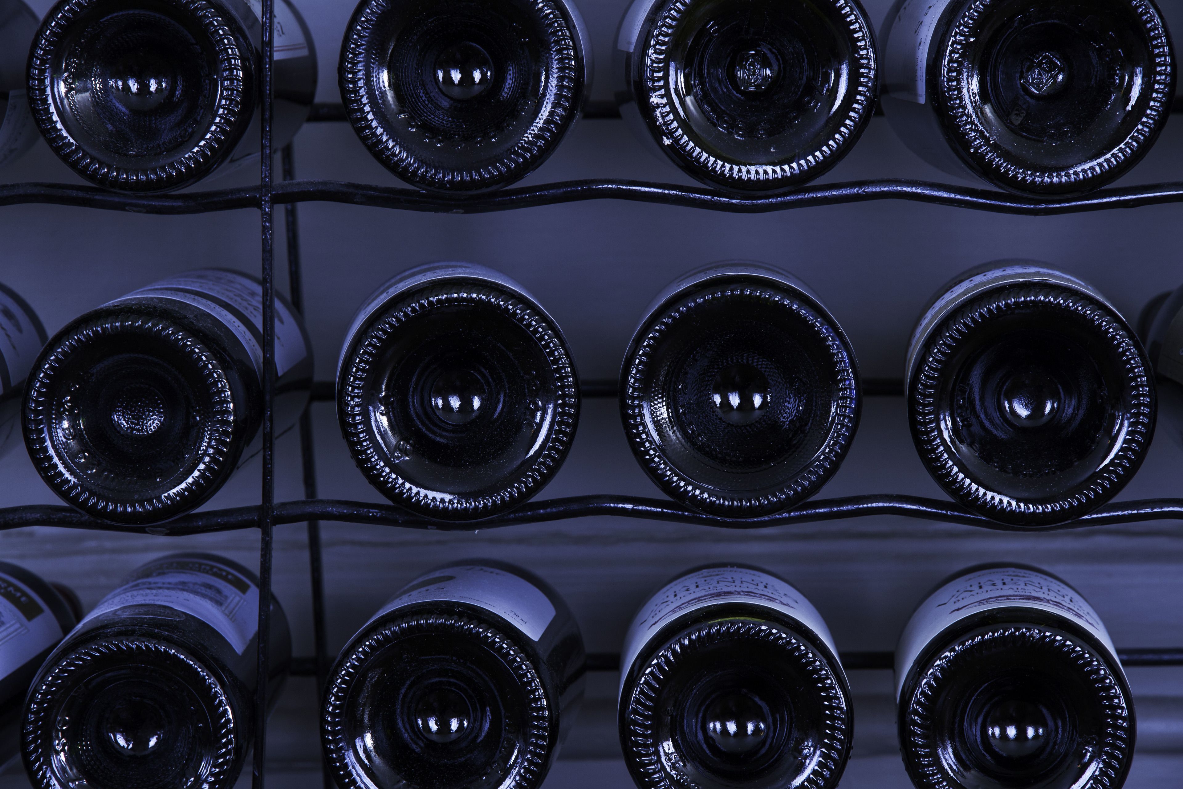 A close-up of wine bottles arranged in a grid on a rack.