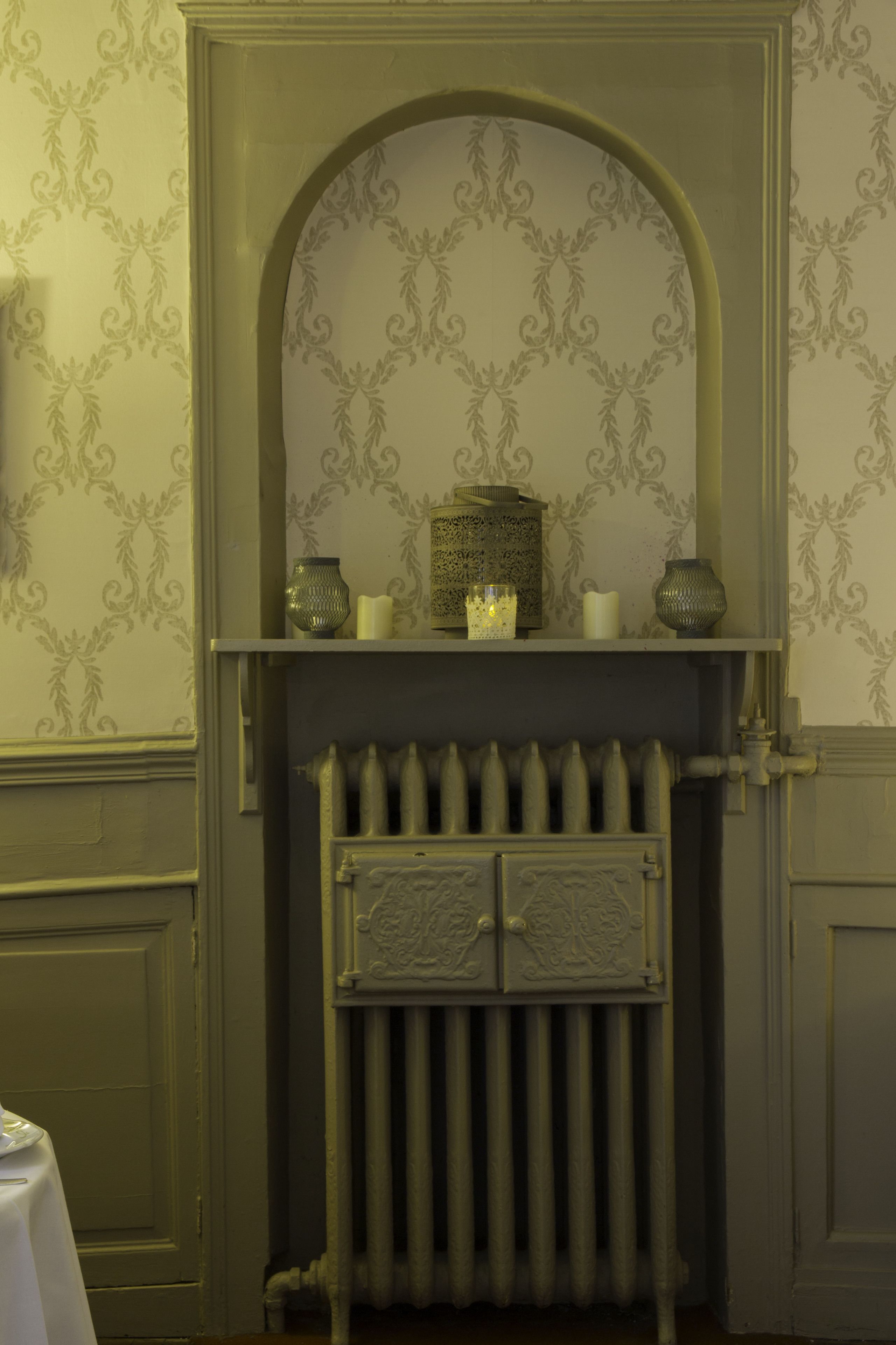Une cheminée agrémentée d’étagères décoratives, un radiateur et un papier peint à motifs.