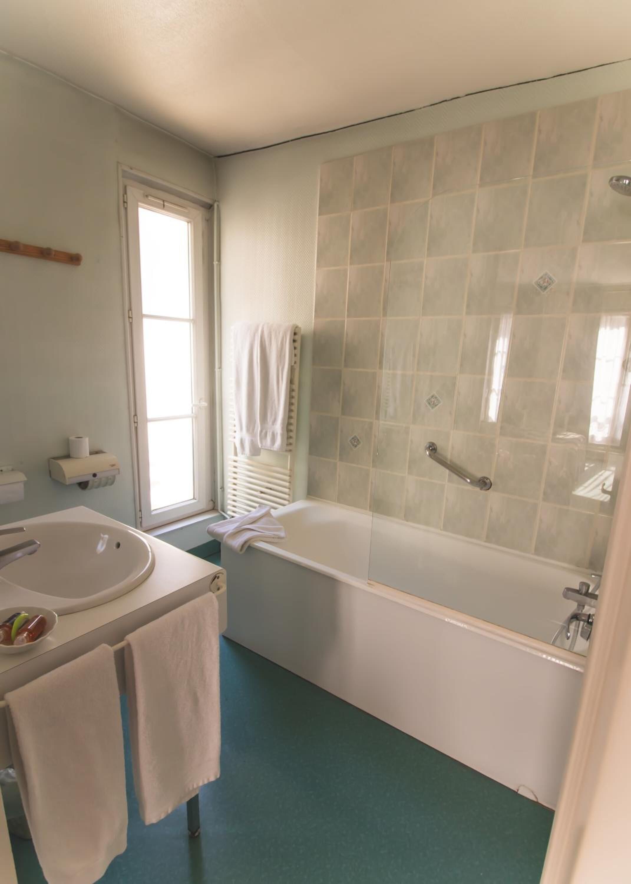 A bathroom with a bathtub, a sink, and a window.
