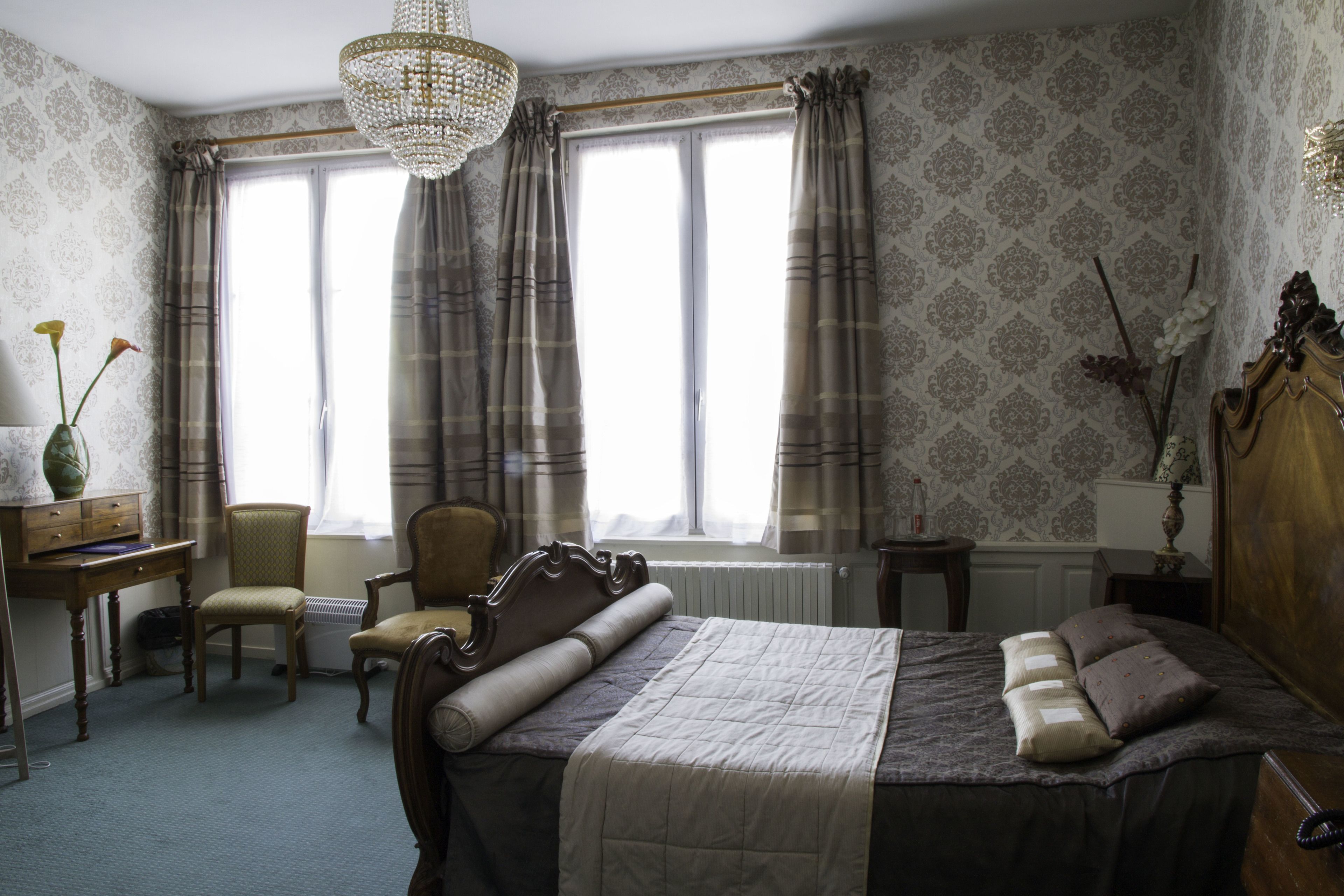 A bedroom with a large bed, a desk, a chair, and a radiator.