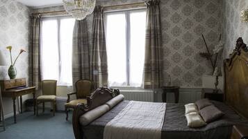 A bedroom with a large bed, a desk, a chair, and a radiator.
