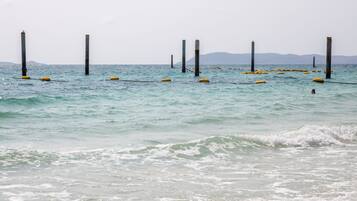 Escena costera con aguas tranquilas, boyas amarillas y postes altos.