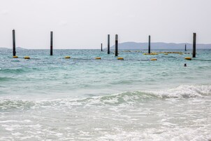Escena costera con aguas tranquilas, boyas amarillas y postes altos.
