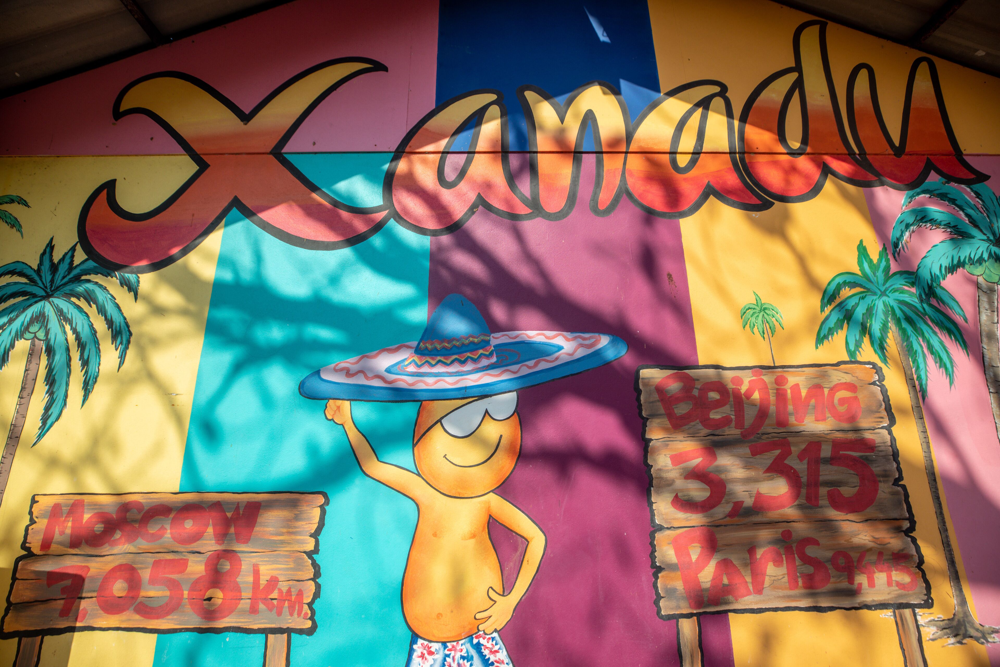 Ein farbenfrohes Wandgemälde mit dem Schriftzug "Xanadu" und einer Comicfigur. Schilder zeigen Entfernungen nach Moskau und Paris.