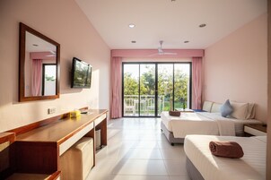 Habitación de hotel con escritorio, dos camas, televisión y balcón con vistas a zonas verdes.